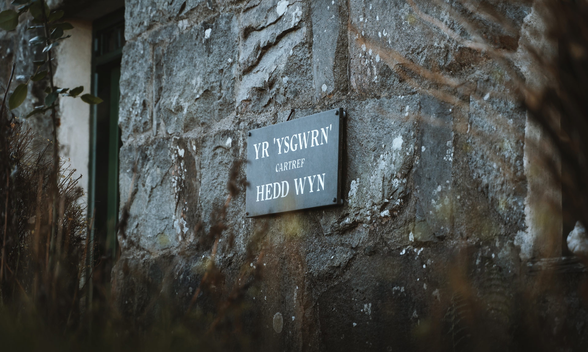 Close-up of a sign on the Ysgwrn farmhouse inscribed with 'Yr Ysgwrn, Hedd Wyn's home'