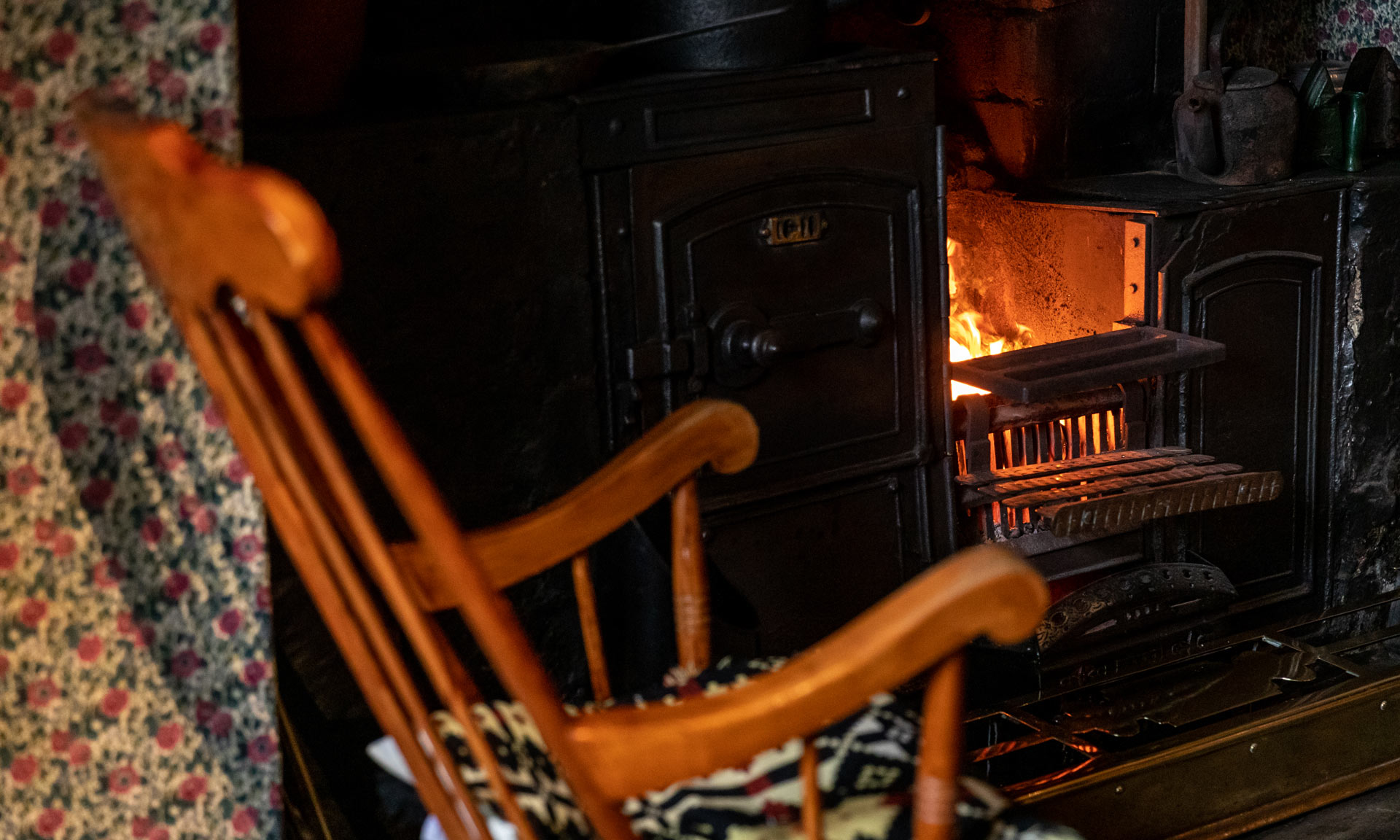A fire roars at Yr Ysgwrn's stove with a rocking chair in the foreground